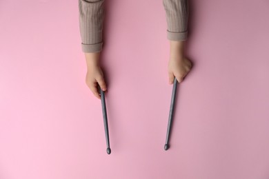 Photo of Little kid holding drumsticks on pink background, top view