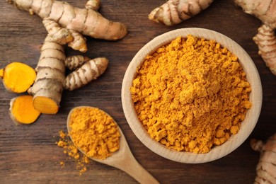 Photo of Aromatic turmeric powder and raw roots on wooden table, flat lay. Space for text