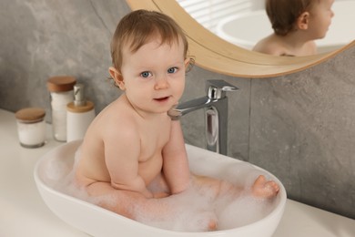 Photo of Cute little baby bathing in sink at home