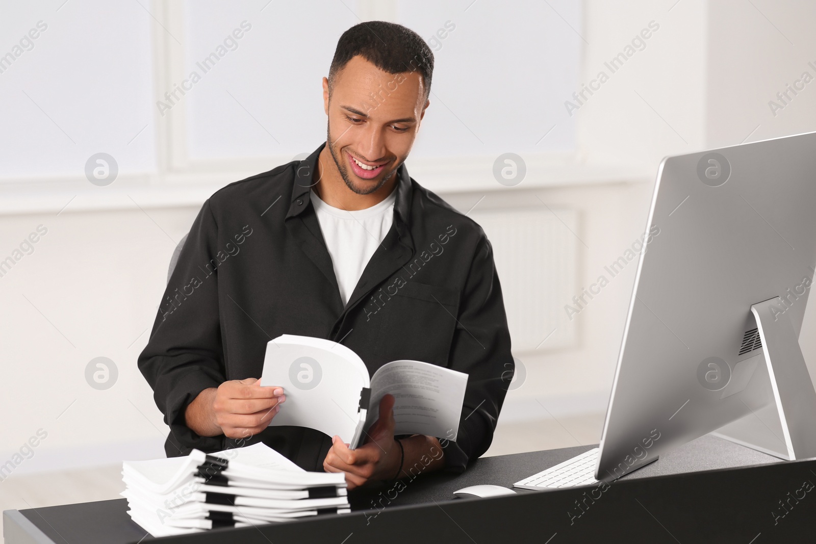 Photo of Happy man working with documents at grey table in office