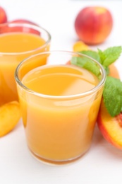 Photo of Natural peach juice and fresh fruits on white wooden table, closeup