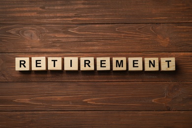 Photo of Cubes with word "RETIREMENT" on wooden background. Pension planning concept