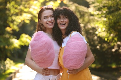Photo of Happy friends with cotton candies spending time together in park on sunny day