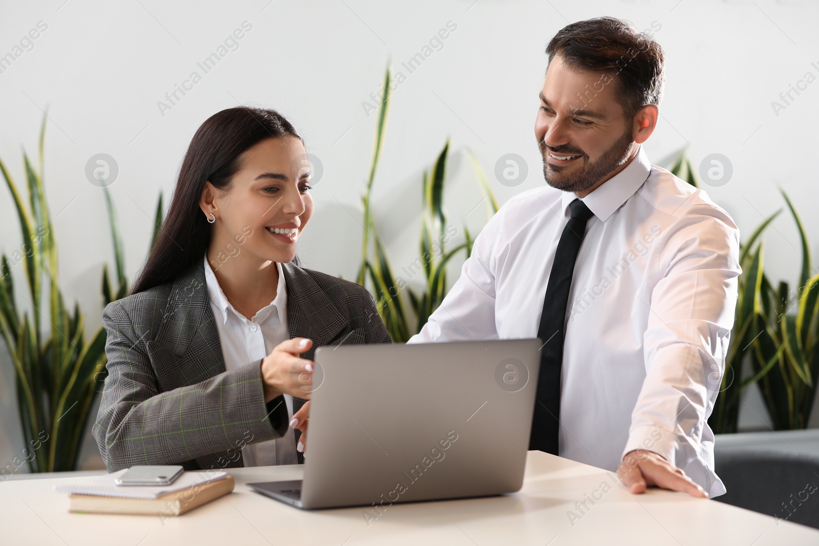 Photo of Colleagues working on laptop at desk in office