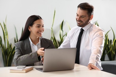 Photo of Colleagues working on laptop at desk in office