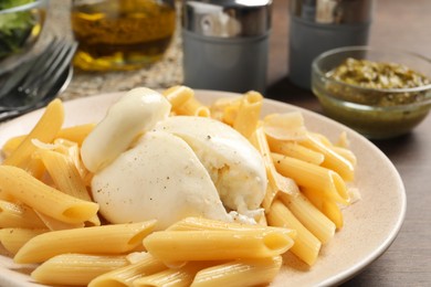 Plate of delicious pasta with burrata on wooden table, closeup