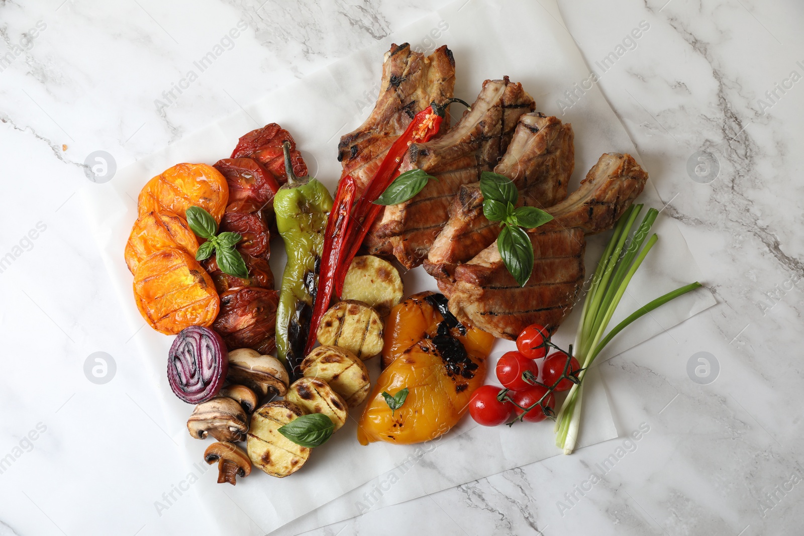 Photo of Delicious grilled meat and vegetables on white marble table, top view