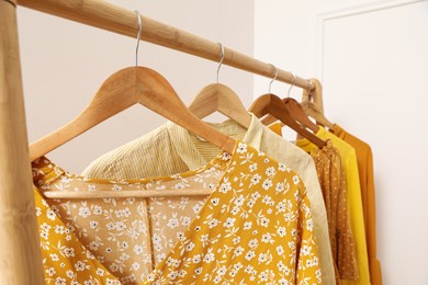 Photo of Wooden rack with hanging clothes indoors. Interior design