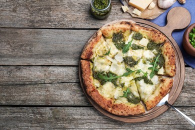 Delicious pizza with pesto, cheese and arugula served on wooden table, flat lay. Space for text