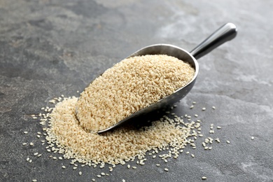 Photo of Metal scoop with white sesame seeds on grey table