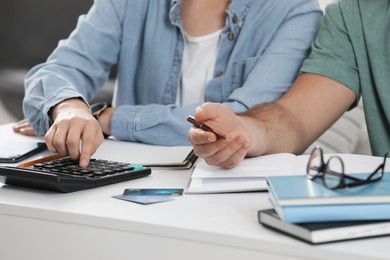 Photo of Young couple discussing family budget at table indoors, closeup