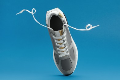Photo of One stylish grey sneaker levitating on blue background