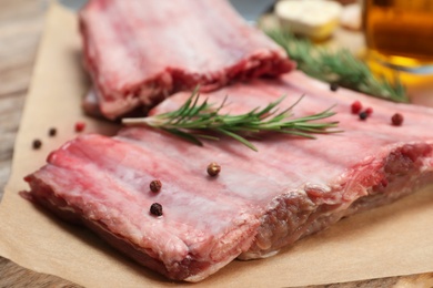 Photo of Raw ribs with pepper and rosemary on parchment, closeup. Fresh meat