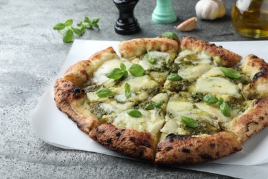 Photo of Delicious pizza with pesto, cheese and basil on grey table