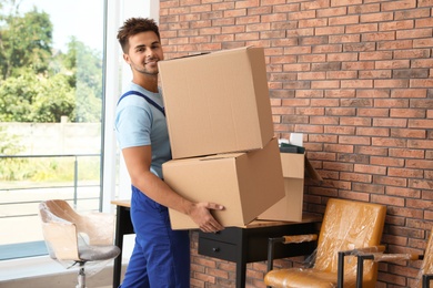 Photo of Young worker carrying cardboard boxes in office. Moving service