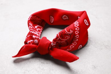 Photo of Tied red bandana with paisley pattern on light table, closeup