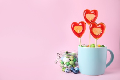 Photo of Cup with different candies on pink background, space for text