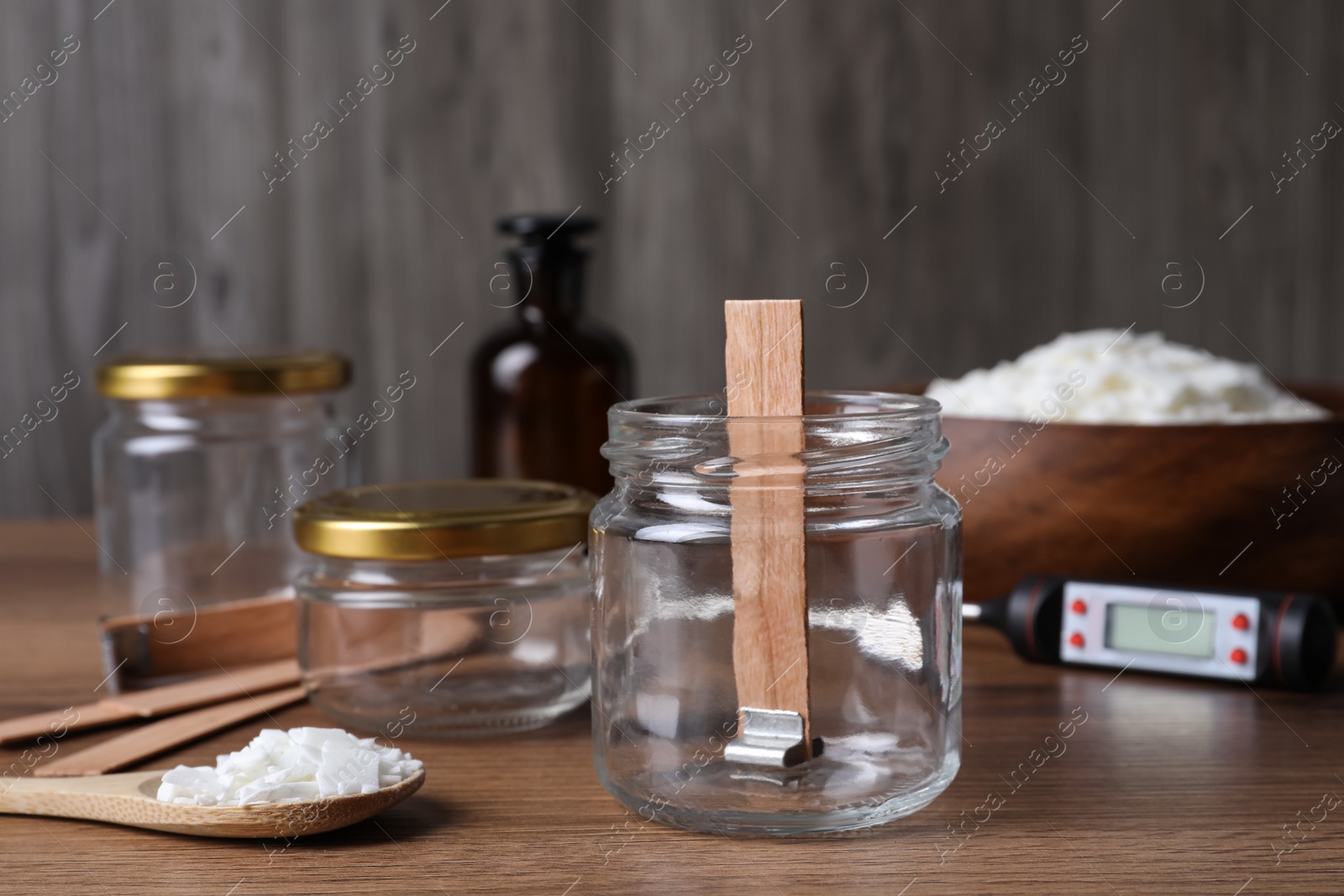 Photo of Glass jar with wick and wax flakes on wooden table. Making homemade candle