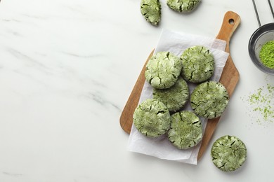 Photo of Board with tasty matcha cookies and powder on white marble table, flat lay. Space for text