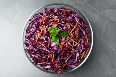 Photo of Bowl with fresh red cabbage salad on grey table, top view