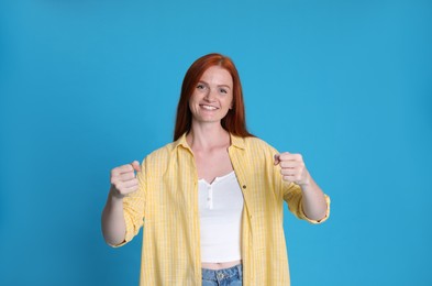 Photo of Happy young woman pretending to drive car on light blue background
