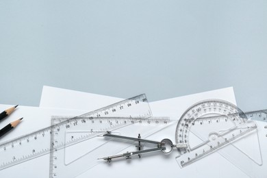 Photo of Flat lay composition with different rulers and compass on light grey background. Space for text