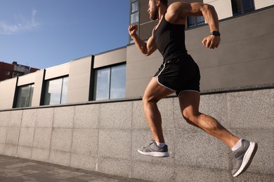 Photo of Young man running near building outdoors. Space for text