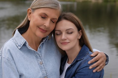 Photo of Happy mature mother and her daughter near pond