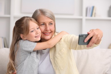 Happy grandmother taking selfie with her granddaughter at home