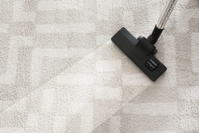 Photo of Hoovering carpet with vacuum cleaner, top view. Space for text