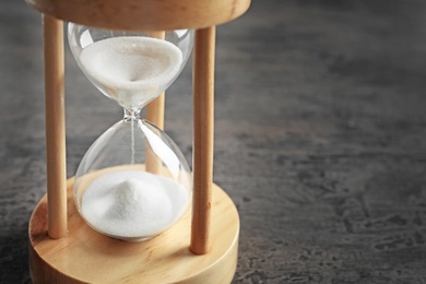 Photo of Hourglass with flowing sand on table. Time management