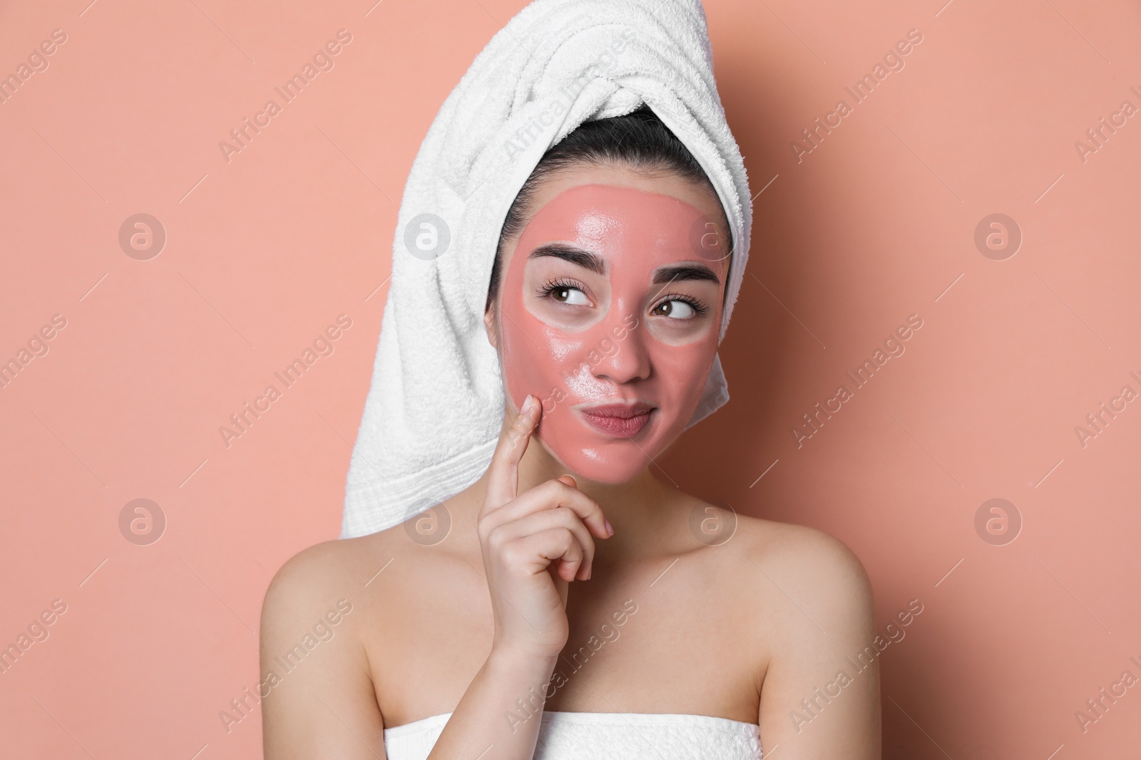 Woman with pomegranate face mask on pale coral background Photo of Woman with pomegranate face mask on pale coral background