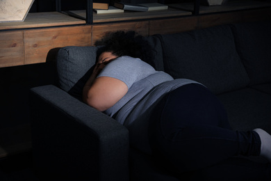 Photo of Depressed overweight woman sleeping on sofa at home