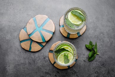 Photo of Glasses of lemonade, mint and stylish cup coasters on grey table, flat lay