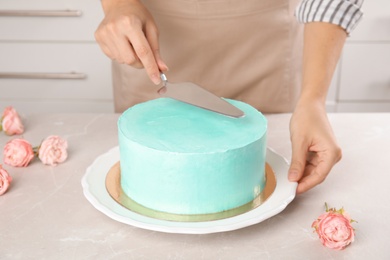 Photo of Woman making fresh delicious birthday cake in kitchen, closeup