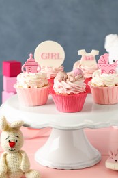 Beautifully decorated baby shower cupcakes for girl with cream and toppers on pink wooden table