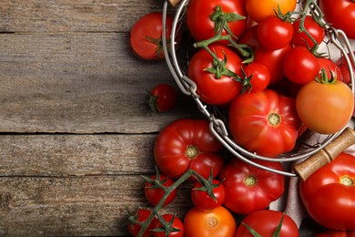 Photo of Many different ripe tomatoes on wooden table, flat lay. Space for text