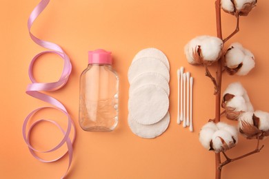 Photo of Flat lay composition with makeup remover and cotton flowers on pale orange background