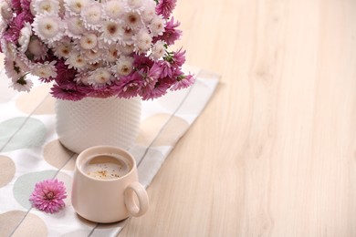 Cup of hot coffee and beautiful bouquet on wooden table. Space for text