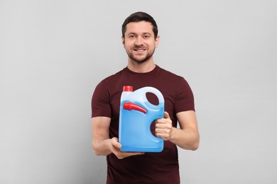 Photo of Man holding canister with blue liquid on light grey background
