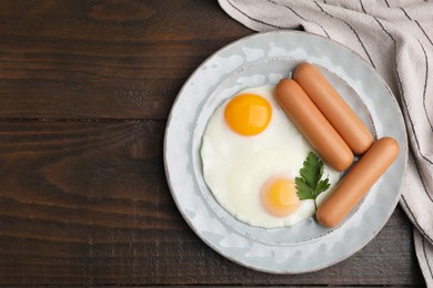 Photo of Delicious boiled sausages, fried eggs and parsley on wooden table, top view. Space for text