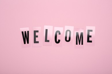Photo of Word Welcome made of plastic letters on pink background, top view