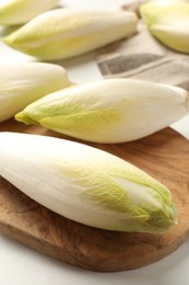 Photo of Raw ripe chicories on white marble table, closeup