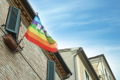 Photo of Beautiful rainbow peace flag hanging on building wall, low angle view