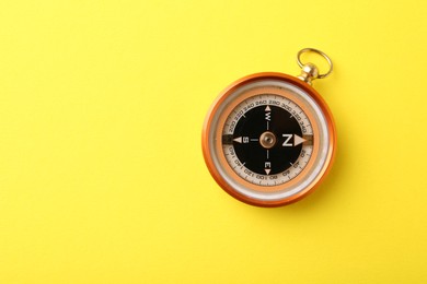 Photo of One compass on yellow background, top view. Space for text