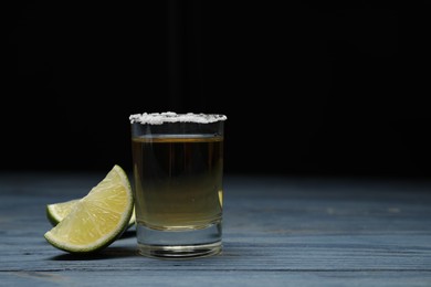 Photo of Mexican Tequila shot with salt and lime on blue wooden table. Space for text