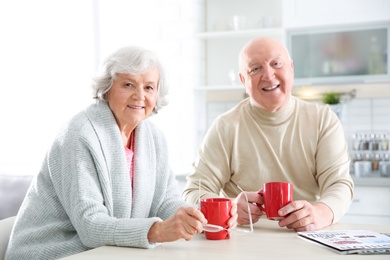 Photo of Elderly couple drinking tea at table in kitchen
