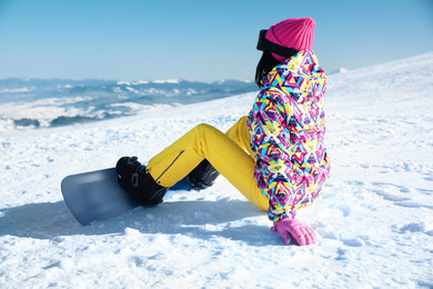 Photo of Young woman with snowboard on hill. Winter vacation