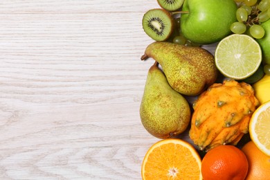 Photo of Many different fresh fruits on light wooden table, flat lay. Space for text