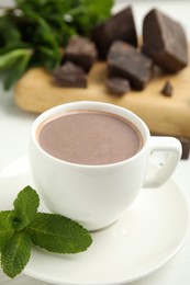 Photo of Cup of delicious hot chocolate and fresh mint on white wooden table, closeup